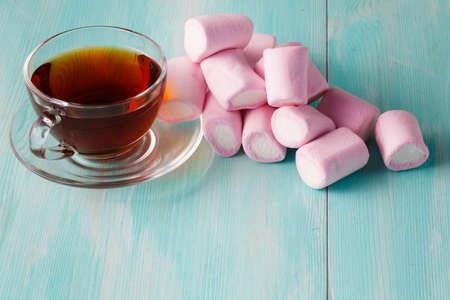 scattered pink marshmalow and cup of tea
