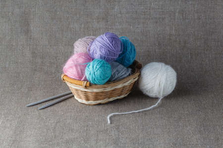 Clews of colored yarn in basket with needleの写真素材
