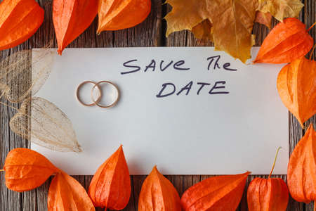 Handwritten words Save the date on paper with fall background, wedding card