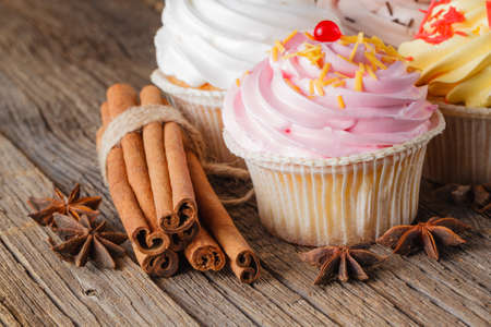 Colored cupcake with cinnamon stick on rustic wooden backgroundの写真素材