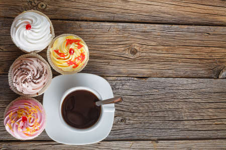 Cupcakes and coffee cup on rustic wooden background. Top viewの写真素材