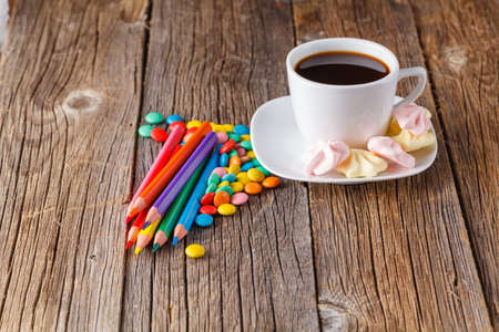 Homemade colorful meringue with decoration and coffee on rustic wooden background