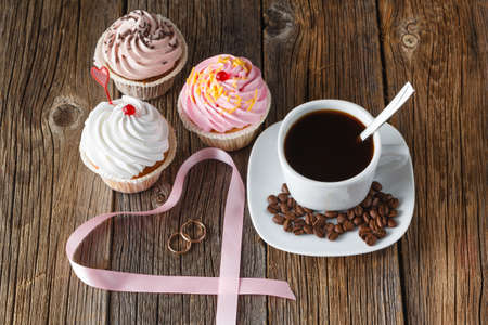Colored cupcake and wedding rings on rustic wooden backgroundの写真素材
