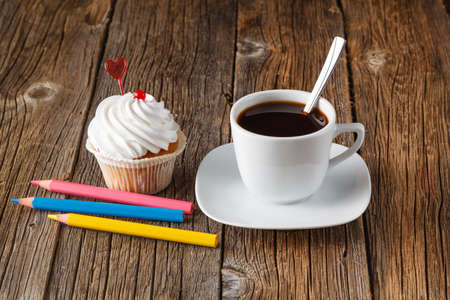 Colored cupcake, coffee cup and color pen on rustic wooden backgroundの写真素材