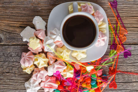 Homemade colorful meringue with decoration and coffee on rustic wooden backgroundの写真素材