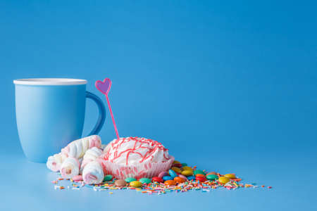 Many colored sweets and mug on blue backgroundの写真素材