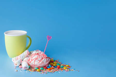 Many colored sweets and mug on blue backgroundの写真素材