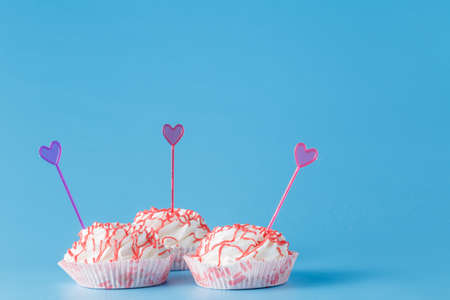 Thee colored cake on blue background with heart decorationの写真素材