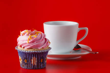 Colored cupcake with tea cup on brigth red backgroundの写真素材