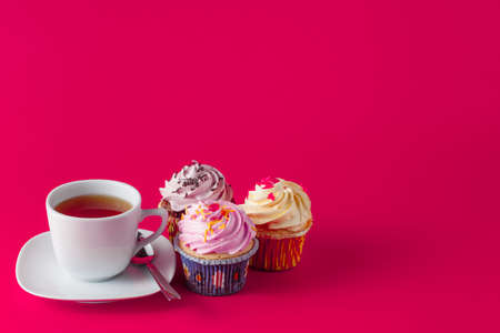 Sweet decoration. Cupcake with tea cup on brigth red background with copyspaceの写真素材