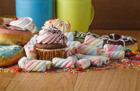 Fun frame with sweets on wooden table. Heap of twisted marshmallowの写真素材