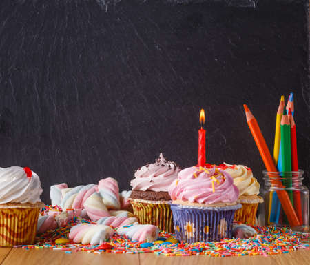 Sweets with copy space on black slate background. Donuts and cupcakesの写真素材