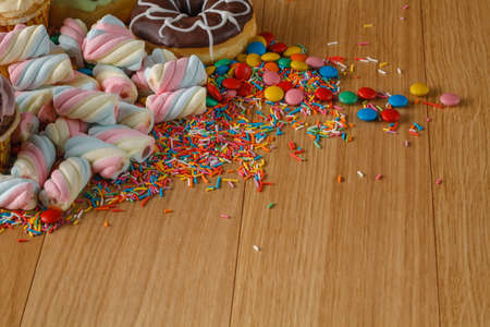 Fun frame with sweets on wooden table. Heap of twisted marshmallowの写真素材