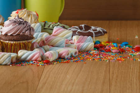 Fun frame with sweets on wooden table. Heap of twisted marshmallowの写真素材