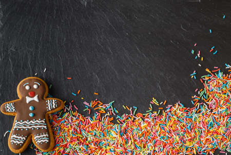 Christmas invitation card with gingerbread man and sweets on black slate