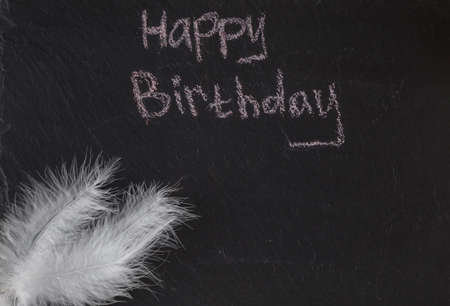 Kid birthday invitation card. Feather on slate backgroundの写真素材