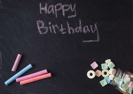 Kid birthday invitation card. Chalk and sweets on slate backgroundの写真素材