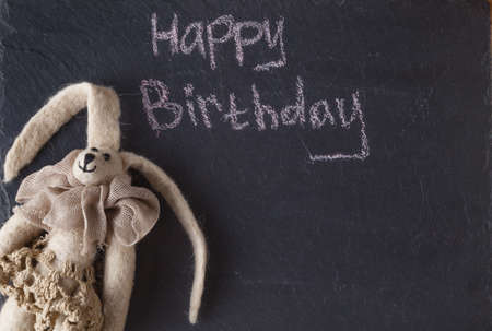 Kid birthday invitation card. Doll on slate backgroundの写真素材