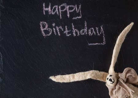 Kid birthday invitation card. Doll on slate backgroundの写真素材