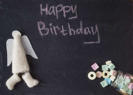 Kid birthday invitation card. Sweets and angel on slate backgroundの写真素材