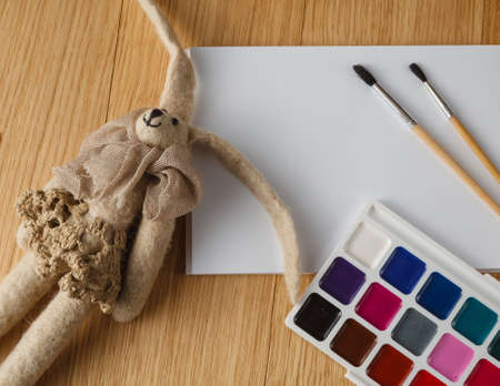 Kid painting concept. Paints with brush on table with felt cozy dollの写真素材