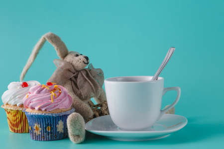 Nostalgic breakfast concept. Rabbit doll and cupcakes with cup of coffeeの写真素材