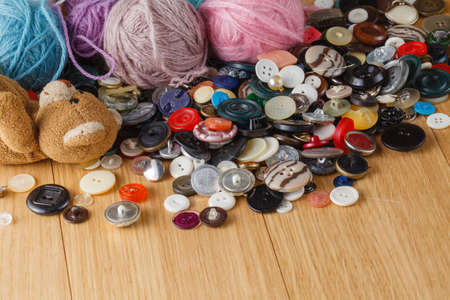 Hobby concept. Many buttons on wooden table with dools and copyspaceの写真素材