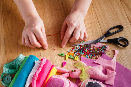 Female hand with needlework objects on wood table