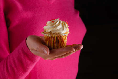 woman hold heap of sweets and give colored sweetsの写真素材