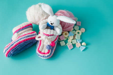 Newborn announcement concept. Knitted booties on aquamarine background with sweetsの写真素材