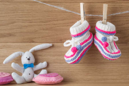 Baby booties hanging on a rope with paper note for invitationの写真素材