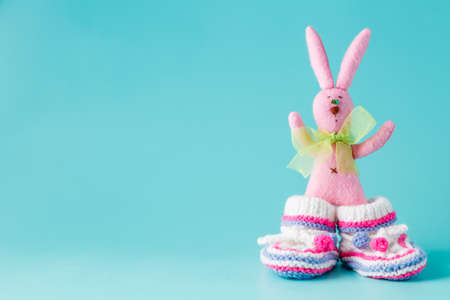 Funny bunny in baby booties on aquamarine backgroundの写真素材