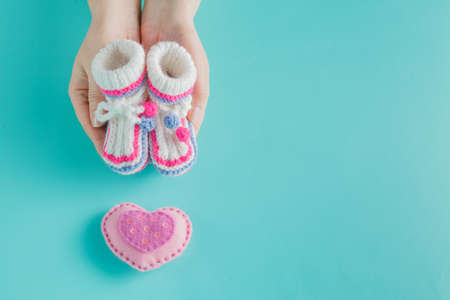 Newborn announcement. Female hands holding tiny knitted bootiesの写真素材