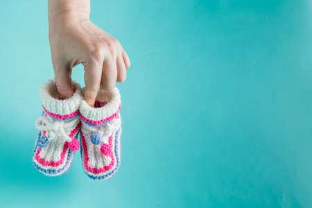 Newborn concept. Female hands holding tiny knitted booties