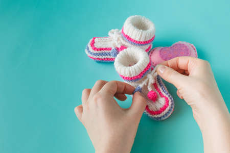 Newborn announcement. Female hands holding tiny knitted bootiesの写真素材