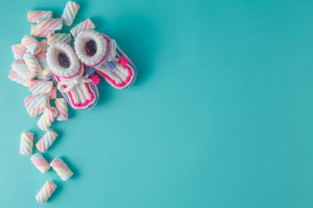 Baby birthday invitation. Knitted booties with sweet marshmallow