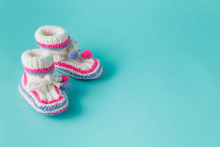 Newborn boy announcemet. Knitted booties on bright aquamarine background