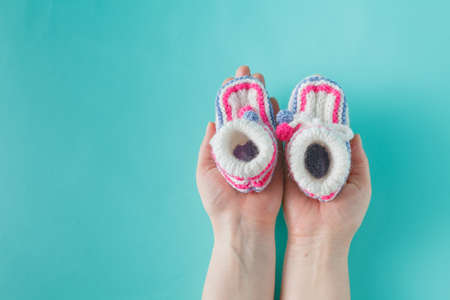 Newborn invitation concept. Female hands holding tiny knitted booties