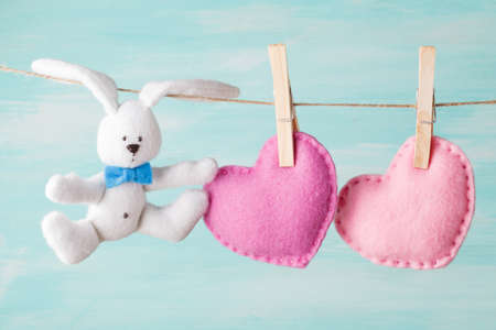 Red paper heart hanging on the clothesline. On aquamarine wood backgroundの写真素材