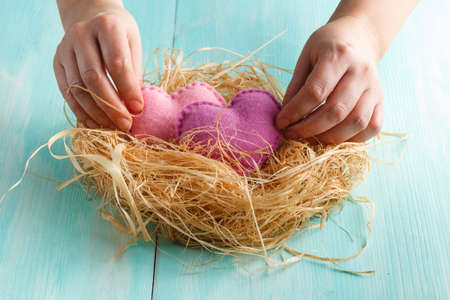 Closeup photo of female holding red knitted heart in hands at nest