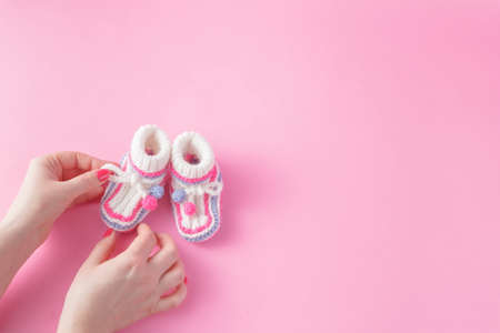 Newborn care concept. Female hands carefully holing baby shoes