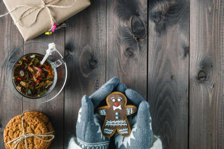 Female hold cookies gingerbread man in hands, rustic wooden backgroundの写真素材