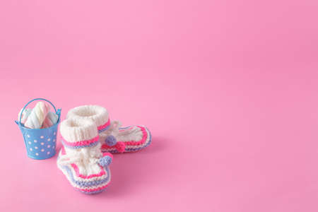 Newborn invitation concept. Small foot wear with toy on pink background