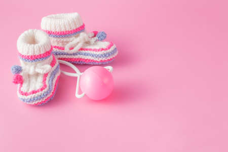 Newborn invitation concept. Small foot wear with toy on pink backgroundの写真素材