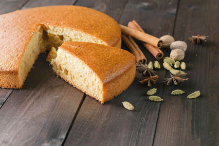 Cooking recipe ingredients. spices pie with cut slice on wood background