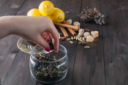 Woman strew herbal tea in glass jar