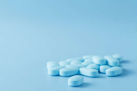 pile of little oval blue pills viewed from the side, focus fades slightly to rear