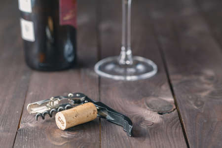 Corkscrew wine bottle and glass on the wooden table. Dark toned