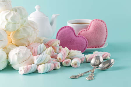 Valentines day breakfast. marshmallow on aquamarine background with cup of tea a?? toy heartsの写真素材