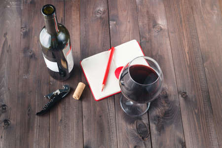 Red wine glass and notebook on tableの写真素材